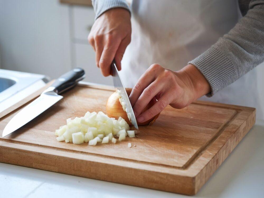 ręce krojące cebulę